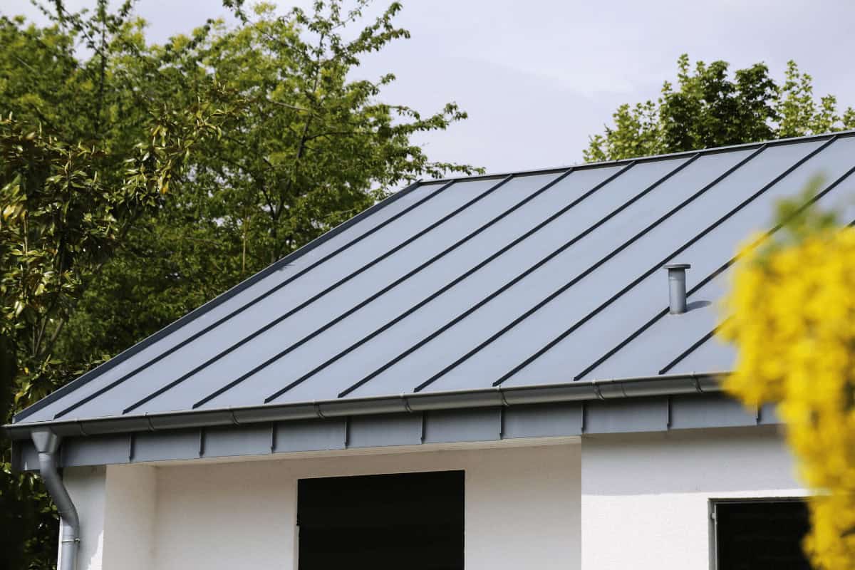 A Cornerstone Metals roof makes this modern house look durable and stylish, with trees adding to the inviting feel.